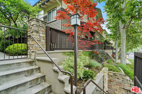 Front view of a multi-level townhouse with stairs and landscaping.