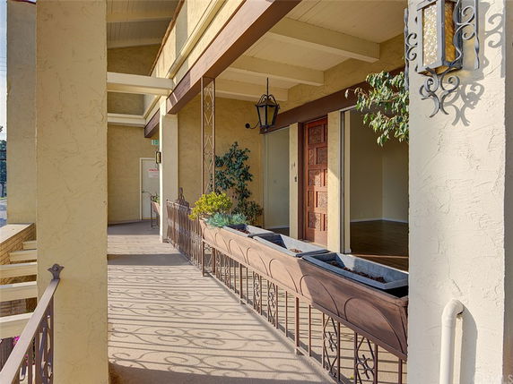 Front view of a building entryway with intricate metal railings and decorative planters.