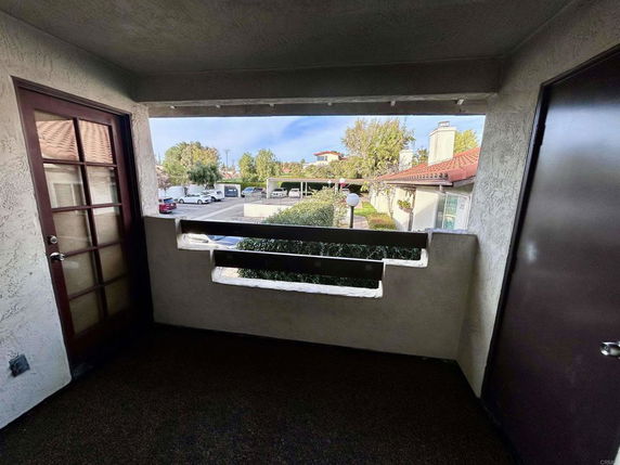 View from a balcony overlooking a small parking area and neighboring houses.