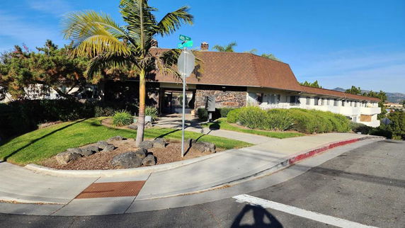 Front view of a single-story building with a sloped roof and landscaped surroundings.