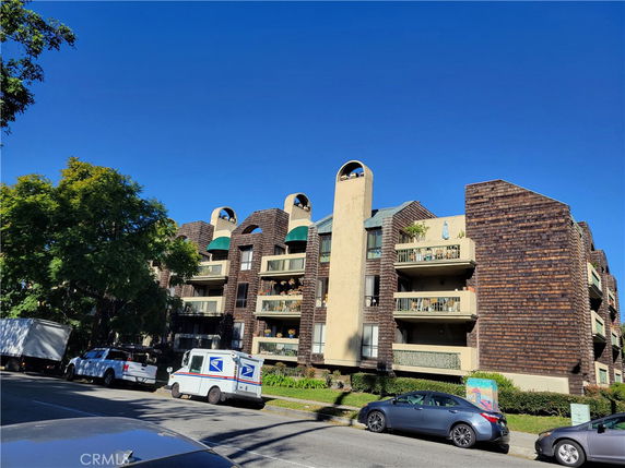 Front view of a multi-story residential building with balconies and brick exterior.