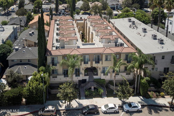 Front view of a large multi-story building with Mediterranean-style architecture, featuring several units and a central walkway.