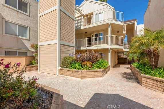 Front view of a residential building with multiple balconies and landscaped planters.
