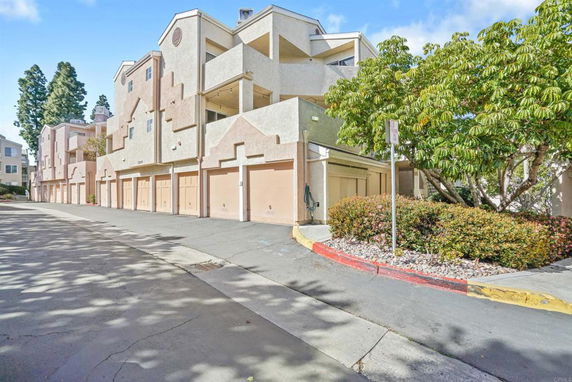 Front view of a multi-story residential building with several garages on the ground level.