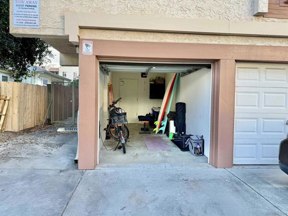 Open garage with items stored inside, including bicycles and surfboards.