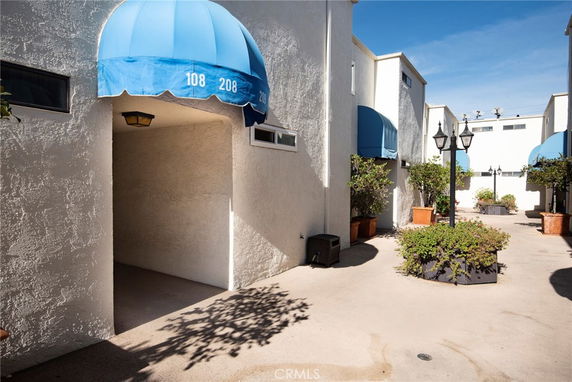 Front view of a building with blue awnings and lamp posts in a courtyard area.