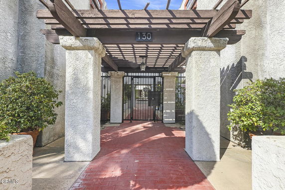 Front view of a building entrance with a pergola and gated entry.