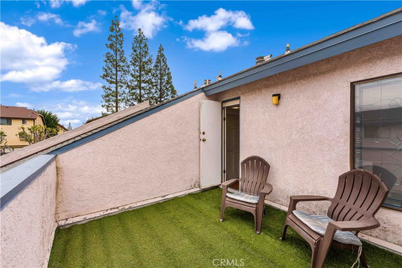 Rooftop area with artificial grass and two chairs.