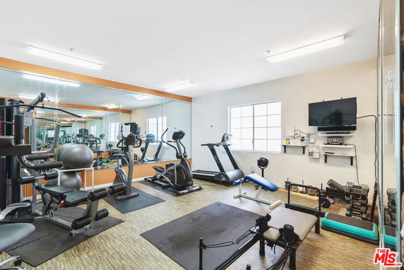 Indoor gym area with exercise equipment and mirrored walls.