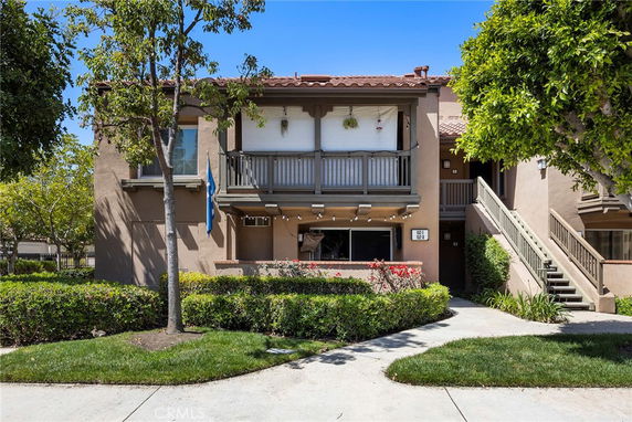 Front view of a two-story residential building with balconies and external stairs.