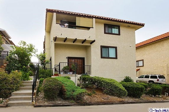 Front view of a two-story house with a decorative balcony and a double-door entry.