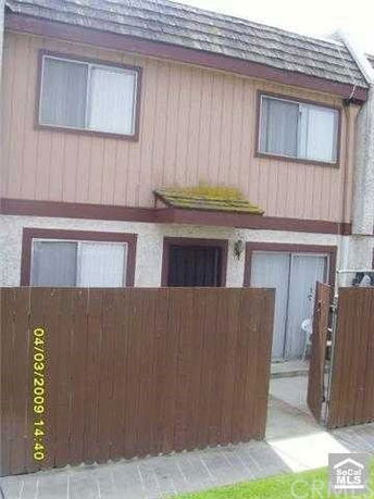 Front view of a two-story house with wooden siding and a small gate.
