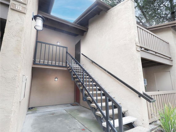Exterior view of a two-story building with stairs leading to the second floor entry.