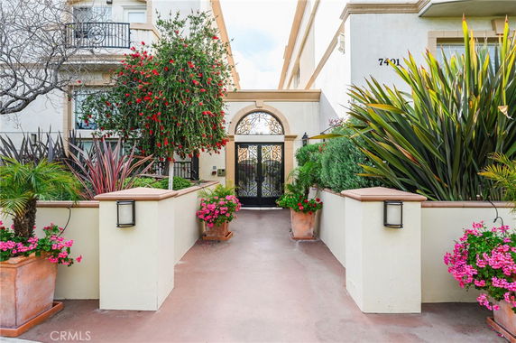 Front view of a house entrance with decorative plants and an ornate metal gate.