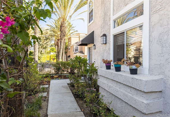 Side view of a two-story house with a pathway, plants, and large windows.