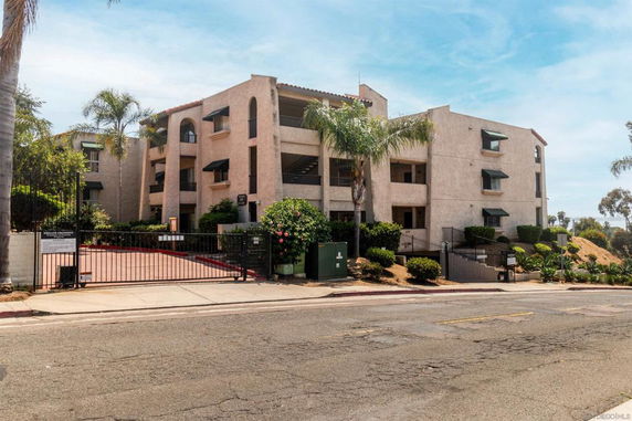 Front view of a multi-story apartment building with a gated entrance.