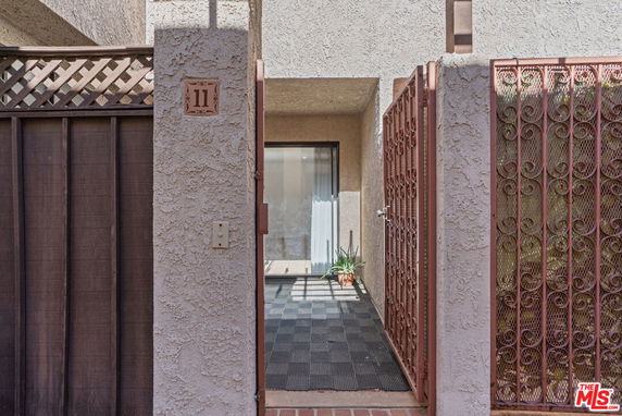 Front view of a building entrance with decorative metal gate and textured walls.