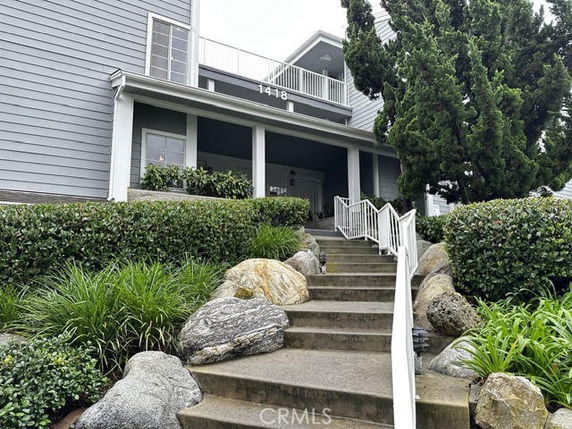 Front view of a multi-story building with exterior stairs and a porch.