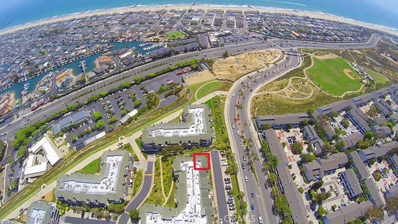Aerial panoramic view of a coastal urban area with buildings, roads, and a harbor in the distance.