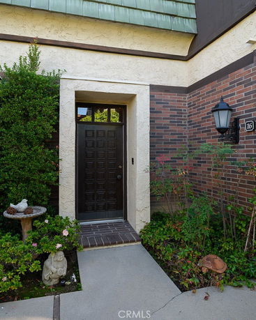 Front view of a house with a dark wooden door and brick and stucco exterior.
