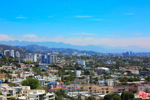 Panoramic view of a cityscape with various buildings and mountains in the background.
