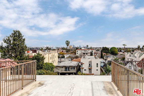Panoramic view of a cityscape from a rooftop with buildings and trees.