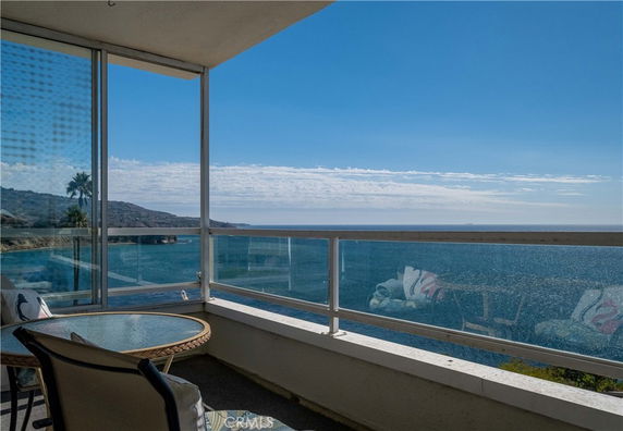Balcony view overlooking the ocean with distant hills.