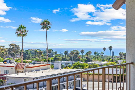 View of palm trees and the ocean from a building balcony.