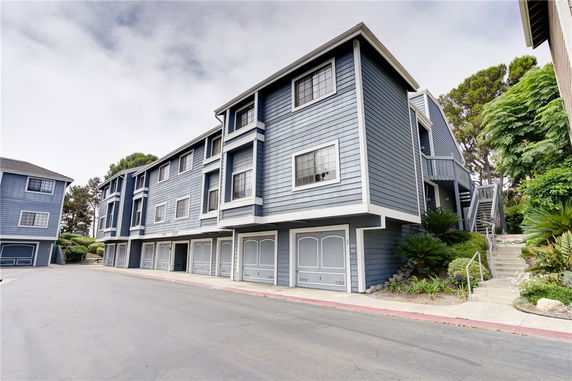 Front view of a multi-story building with garages on the ground level.