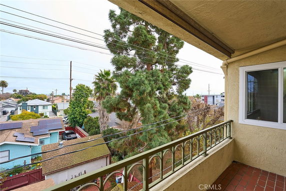 View from a balcony overlooking a neighborhood with trees and houses.