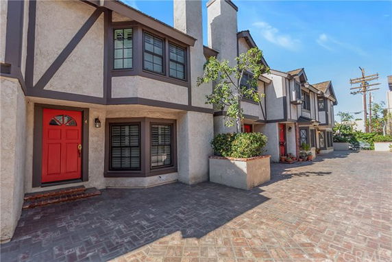 Front view of a multi-story residential building with red doors and bay windows.