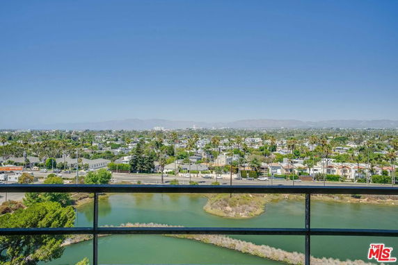 Panoramic view of a landscape with buildings, greenery, and a body of water in the foreground.