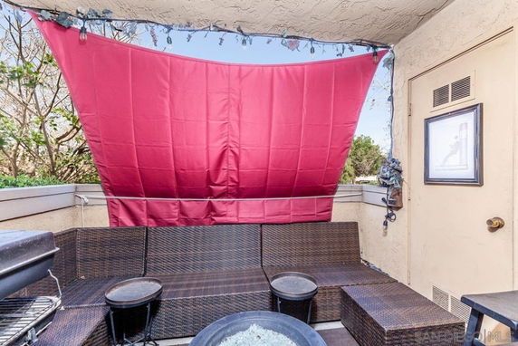Outdoor seating area with a red curtain and wicker furniture on a balcony.