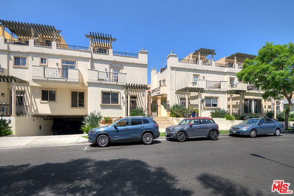 Front view of a multi-story residential building with balconies and pergolas.