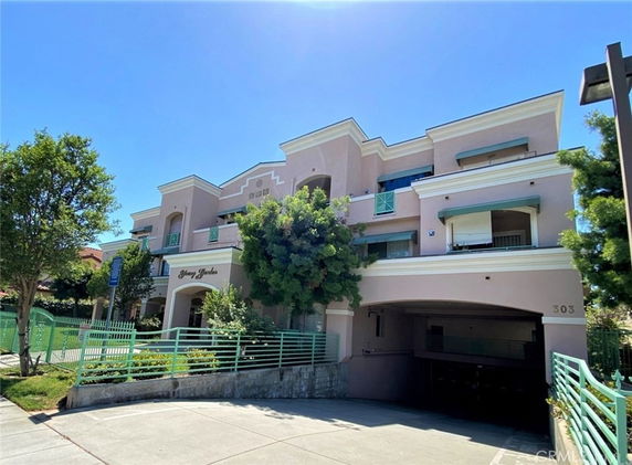 Front view of a multi-story residential building with balconies and a parking entrance.