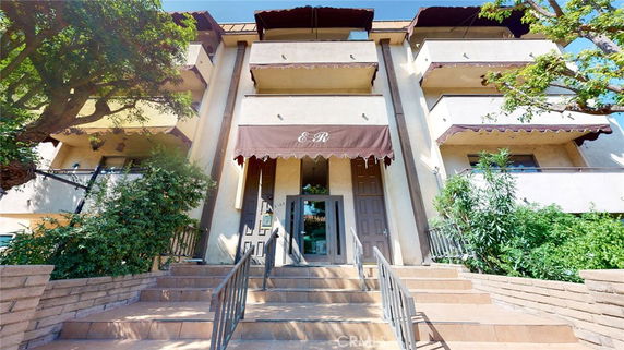 Front view of a multi-story building with balconies and an entrance canopy.