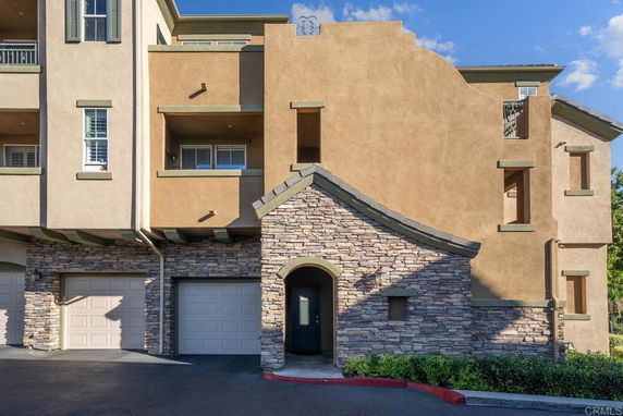 Front view of a multi-story building with stone and stucco exterior.