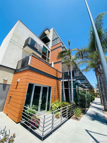 Front view of a modern multi-story building with large windows and orange paneling.