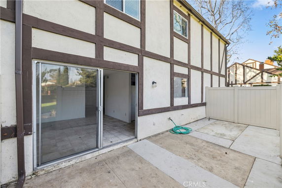 Exterior view of a two-story building with sliding glass doors and a small concrete patio area.