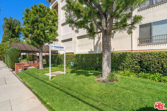 Front view of a multi-story condominium building with a sign labeled 'Parkside Condominiums.'