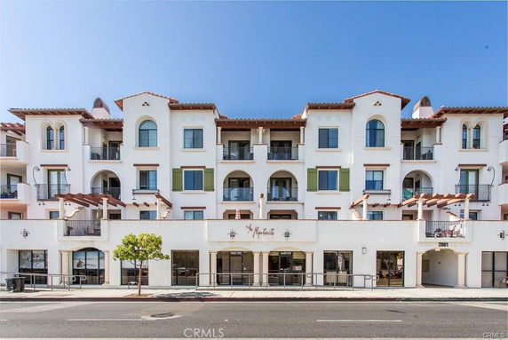 Front view of a multi-story building with numerous balconies and large windows.