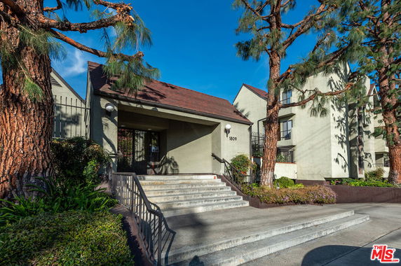 Front view of a multi-story building with entrance steps and surrounding trees.