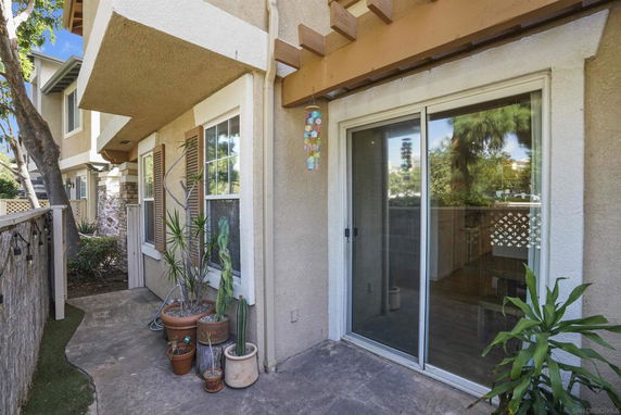 Corner view of a two-story house with sliding glass doors and a small patio area.