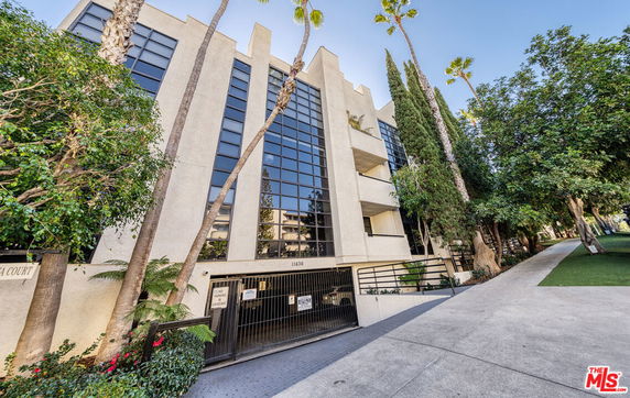 Front view of a multi-story building with large windows and a gated entrance.