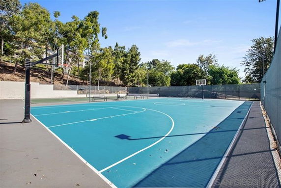 Basketball court with trees and fencing surrounding it.