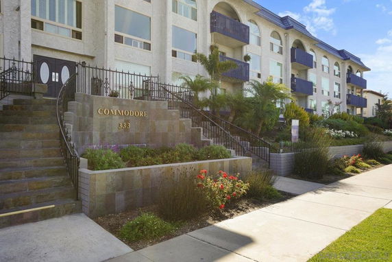 Front view of a multi-story residential building with balconies and a staircase entrance.