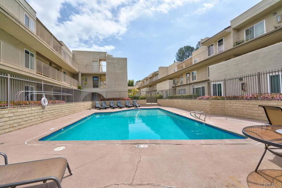 Outdoor swimming pool area surrounded by multi-story residential buildings.