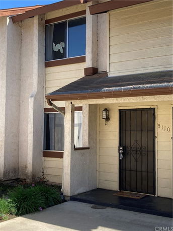 Front view of a two-story house with a covered entryway and decorative metal door.