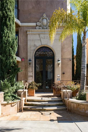 Front view of a building with an ornate entrance and tall greenery.
