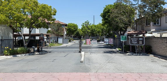 Front view of a gated residential community entrance with houses on either side.